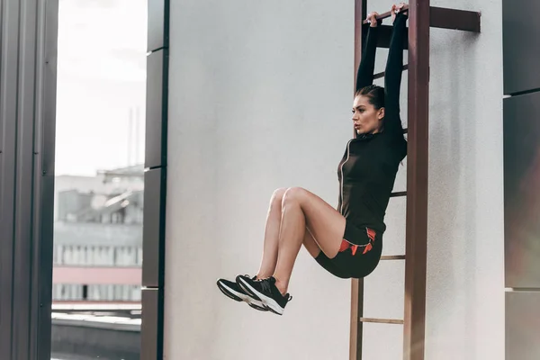 Привлекательная спортсменка делает пресс на лестнице на крыше — стоковое фото
