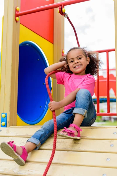 Sonriente afroamericano pequeño niño divertirse en patio de recreo - foto de stock