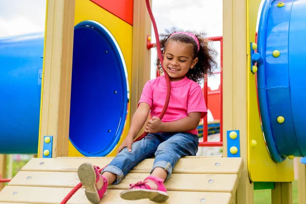 Feliz encaracolado afro-americano pequena criança se divertindo no parque infantil — Fotografia de Stock