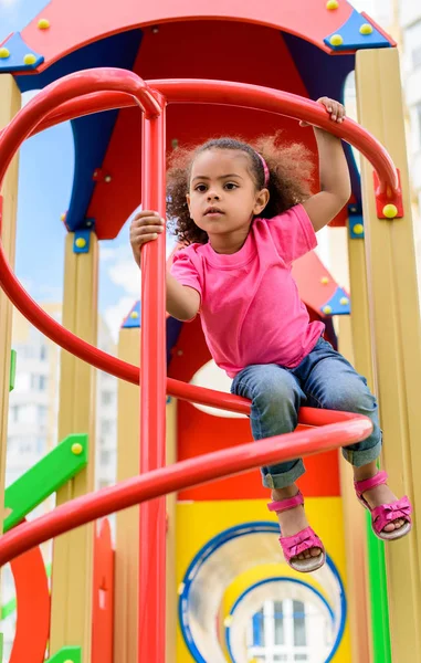 Vista de ángulo bajo de rizado niño afroamericano que se divierte en el patio de recreo — Stock Photo