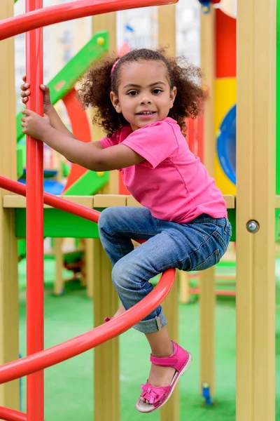 Lächelnd lockiges afrikanisch-amerikanisches Kind, das Spaß auf dem Spielplatz hat — Stockfoto