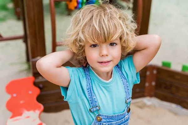 Вибірковий фокус чарівного маленького хлопчика, який дивиться на камеру на дитячому майданчику — стокове фото