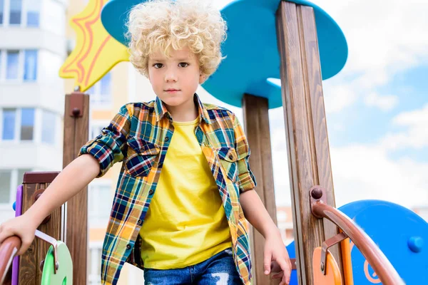 Vista de ángulo bajo de adorable niño rizado divertirse en el patio de recreo - foto de stock