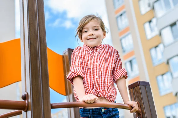 Vue à angle bas du petit enfant souriant s'amusant à l'aire de jeux — Photo de stock