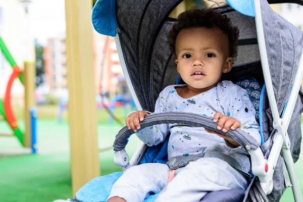 Foyer sélectif de tout-petit afro-américain assis dans un landau à Playgorund — Photo de stock