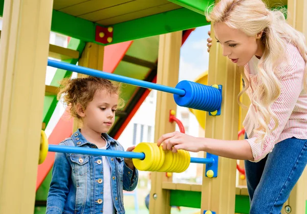 Mother teaching to count little daughter on abacus at playground — Stock Photo