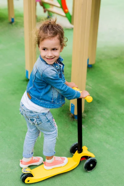 Visão de ângulo alto de criança pequena montando em scooter pontapé no parque infantil — Fotografia de Stock