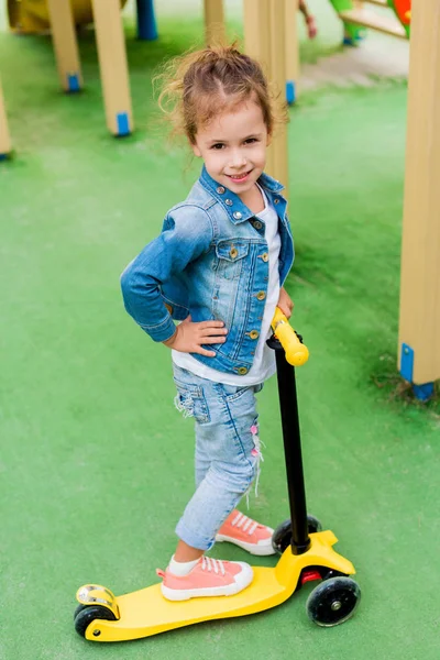 Enfoque selectivo de niño sonriente de pie con patinete scooter en el patio de recreo - foto de stock
