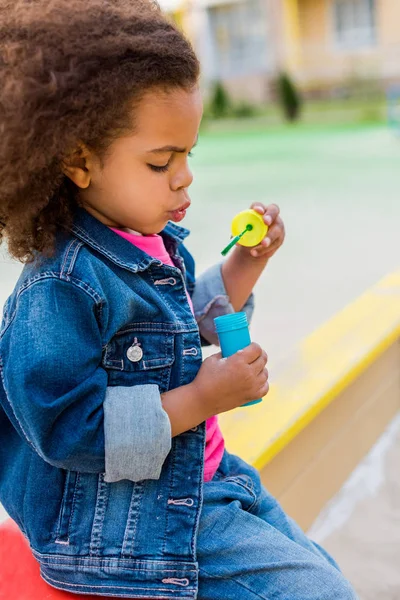 Vista lateral de encaracolado afro-americano criança brincando com bolhas de sabão — Fotografia de Stock