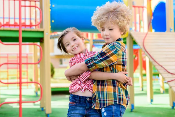 Adorable hermanito y hermana abrazándose en el patio de recreo - foto de stock