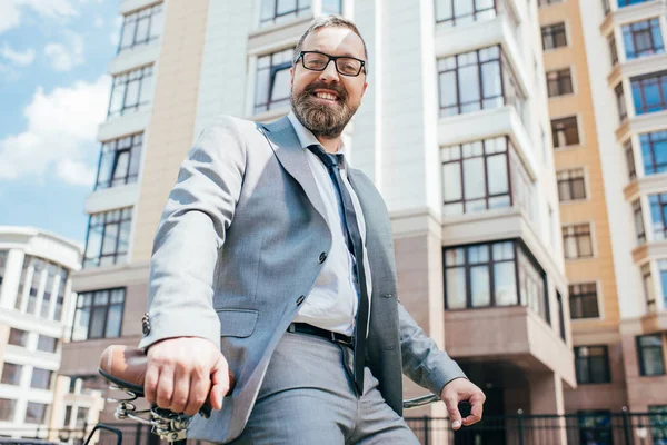 Усміхнений бізнесмен сидить на велосипеді в місті — стокове фото