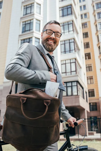 Борода гарний бізнесмен зі шкіряною сумкою та велосипедом у місті — стокове фото