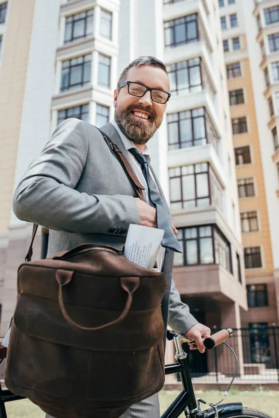 Barba bonito homem de negócios com bolsa de couro e bicicleta na cidade — Stock Photo