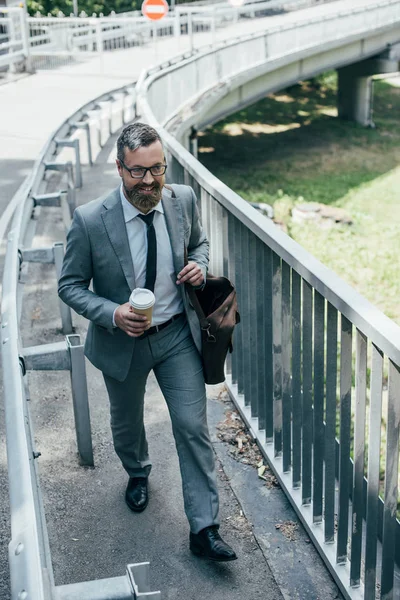 Bell'uomo d'affari in abito formale con borsa in pelle e caffè per andare a passeggiare in città — Foto stock