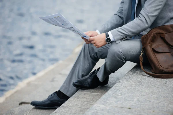 Vista recortada de empresario en traje gris leyendo periódico en muelle - foto de stock