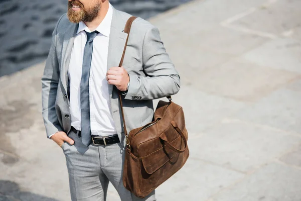 Обрезанный вид бизнесмена с кожаной сумкой, идущего по набережной — стоковое фото