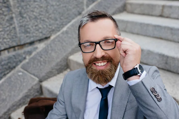 Hombre de negocios sonriente en traje gris y gafas graduadas - foto de stock