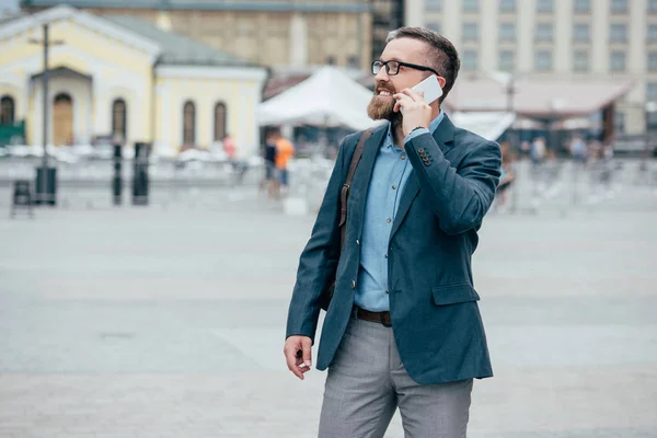 Beard stylish businessman talking on smartphone in city — Stock Photo