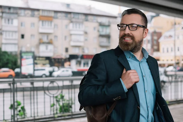 Beard stylish businessman in eyeglasses with leather bag in city — Stock Photo