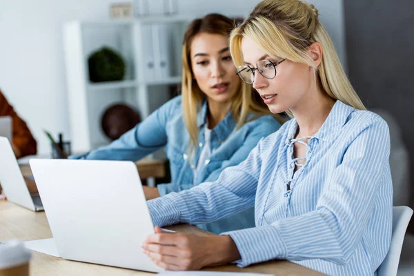 Colegas multiculturais trabalhando no projeto de startup no escritório e olhando para laptop — Fotografia de Stock