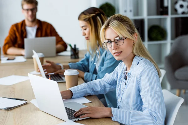 Colegas multiculturales que trabajan en el proyecto de inicio en la oficina y mirando a la cámara - foto de stock