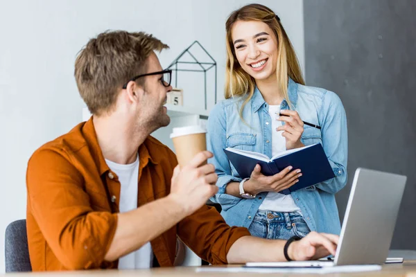 Colegas multiculturales que trabajan en el proyecto de startup en la oficina y se miran entre sí - foto de stock