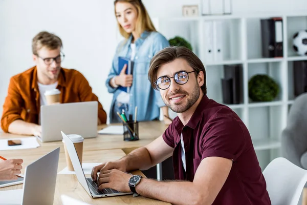 Smiling handsome man working on startup project in office and looking at camera — Stock Photo
