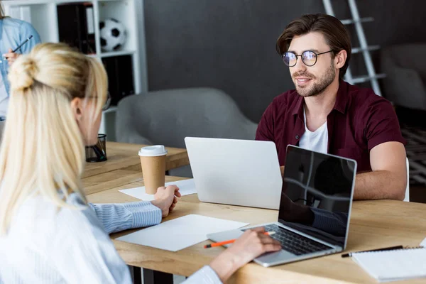 Male and female colleagues working on startup project in office and looking at each other — Stock Photo
