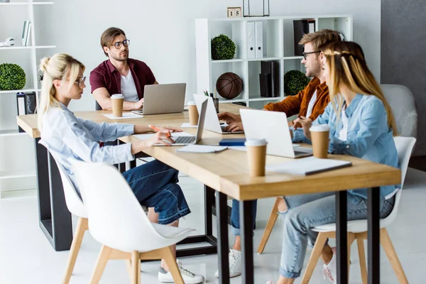 Multicultural colleagues working on startup project in office and using digital devices — Stock Photo