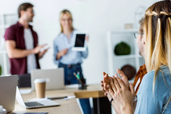 Colleghi che presentano il progetto di avvio su tablet in carica con persone che applaudono in primo piano — Foto stock