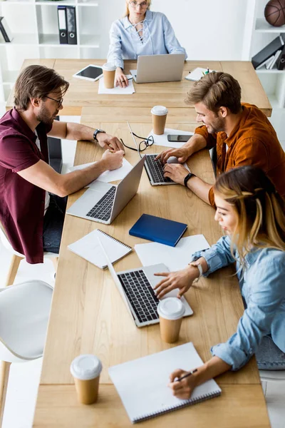 Vista ad alto angolo di giovani colleghi multiculturali che lavorano al progetto di startup in ufficio con gadget — Foto stock