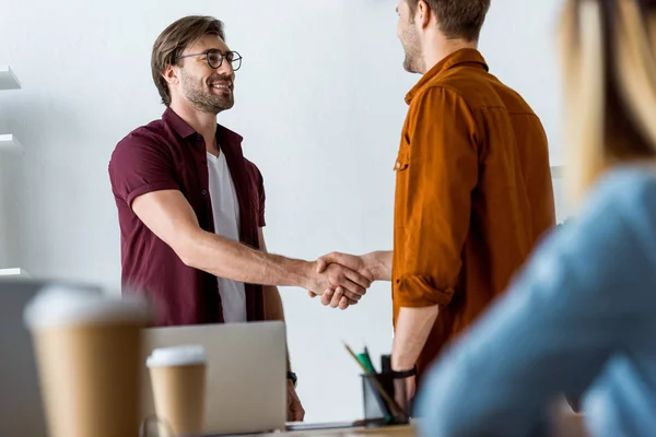 Colleagues working on startup project in office and men shaking hands — Stock Photo