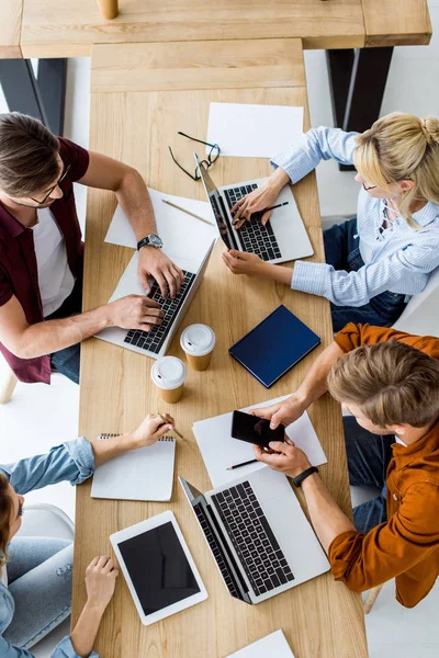 Vista dall'alto dei colleghi che lavorano al progetto di avvio in ufficio e utilizzano gadget — Foto stock