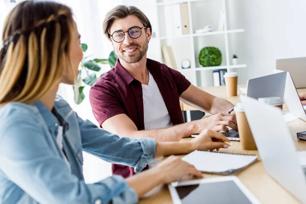 Smiling colleagues working on startup project in office and looking at each other — Stock Photo