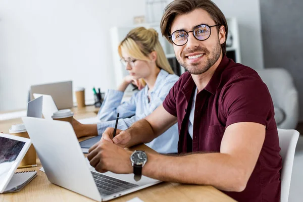 Colleagues working on startup project in office and smiling man looking at camera — Stock Photo