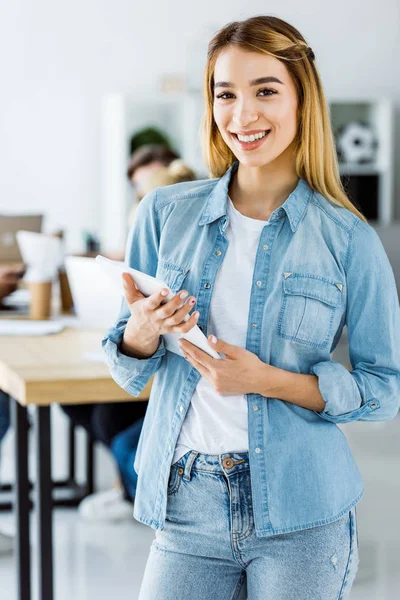 Atractivo asiático mujer de negocios de pie con tableta en start up oficina y mirando a la cámara - foto de stock