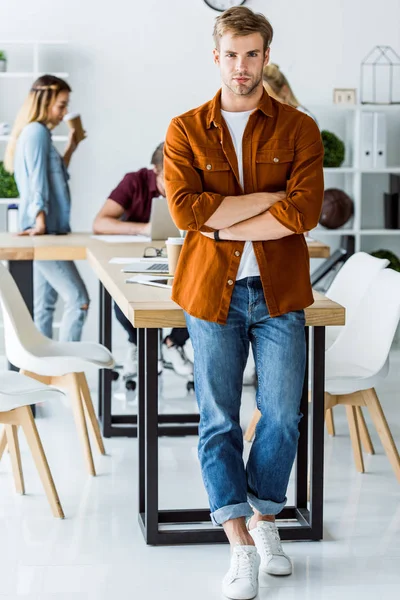 Ernster gutaussehender Mann lehnt an Tisch in Büro-Start-up — Stockfoto