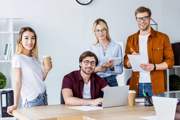 Multicultural colleagues working on startup project in office and looking at camera — Stock Photo