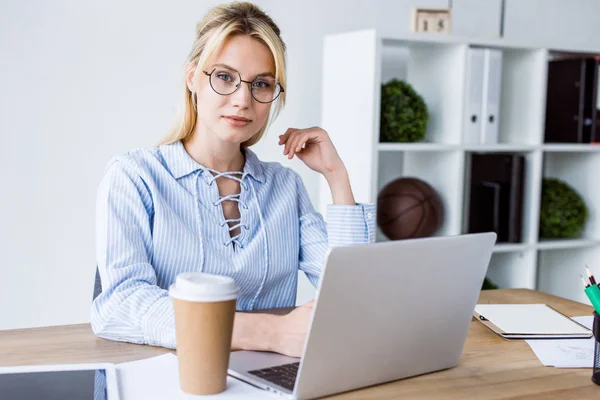 Belle femme d'affaires travaillant sur le projet de démarrage dans le bureau avec ordinateur portable et regardant la caméra — Photo de stock