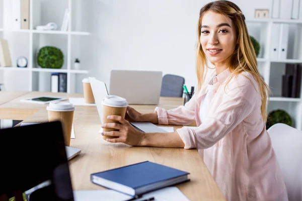 Sorridente donna d'affari asiatica che lavora al progetto start up e guarda la fotocamera in ufficio — Foto stock