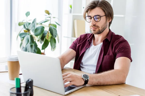 Handsome young businessman working on startup project in office with laptop — Stock Photo