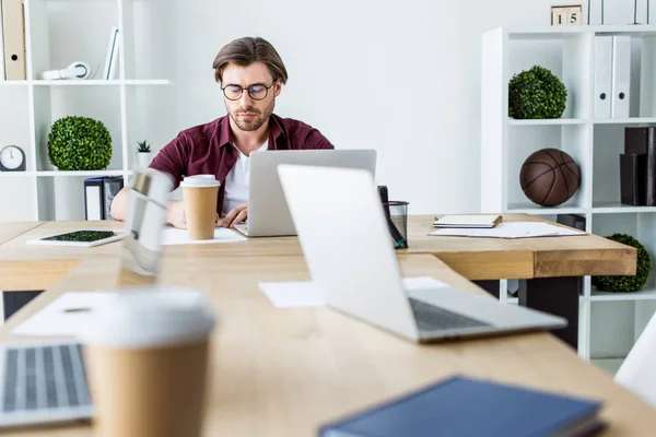 Bell'uomo d'affari che lavora al progetto di startup in ufficio con computer portatili sul tavolo — Foto stock