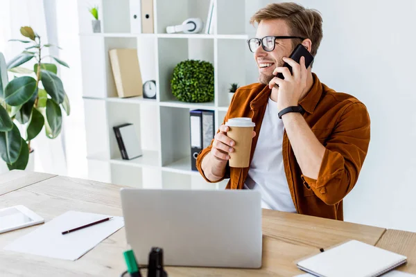 Bel homme d'affaires travaillant sur le projet de démarrage au bureau et parlant par smartphone — Photo de stock