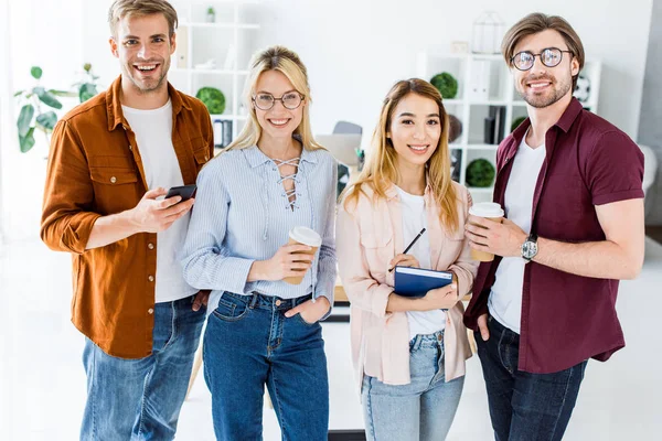 Colegas multiculturales de proyecto de inicio en la oficina mirando a la cámara - foto de stock