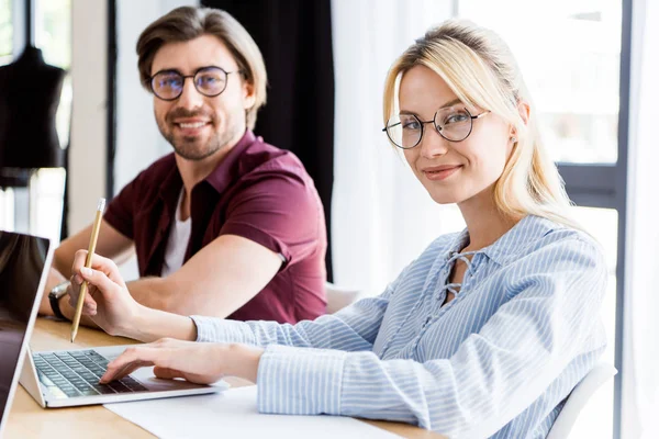 Smiling colleagues working on startup project in office and looking at camera — Stock Photo