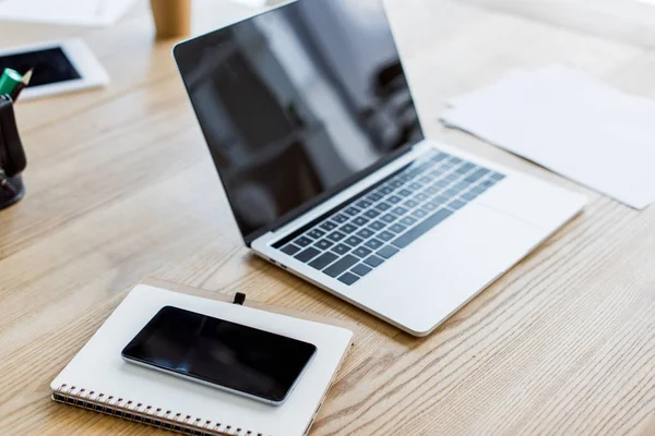 Portátil, smartphone y portátil en la mesa en la oficina de negocios - foto de stock