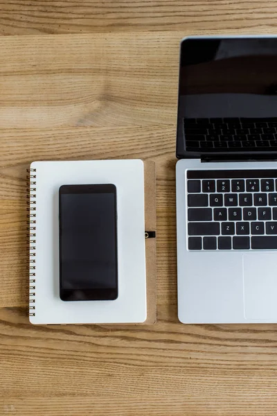 Vista superior de la computadora portátil, smartphone y portátil en la mesa en la oficina de negocios - foto de stock