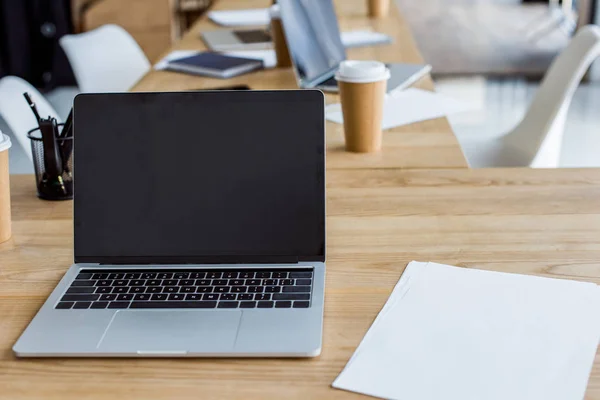 Computer portatile con schermo bianco su tavolo in legno in ufficio — Foto stock