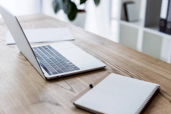 Laptop and notebook on wooden table in business office — Stock Photo