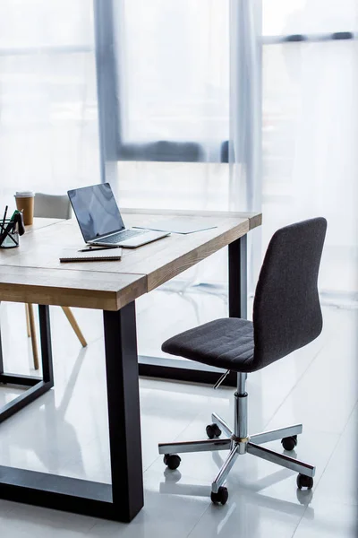 Ordinateur portable et tasse à café jetable sur la table dans le bureau d'affaires — Photo de stock